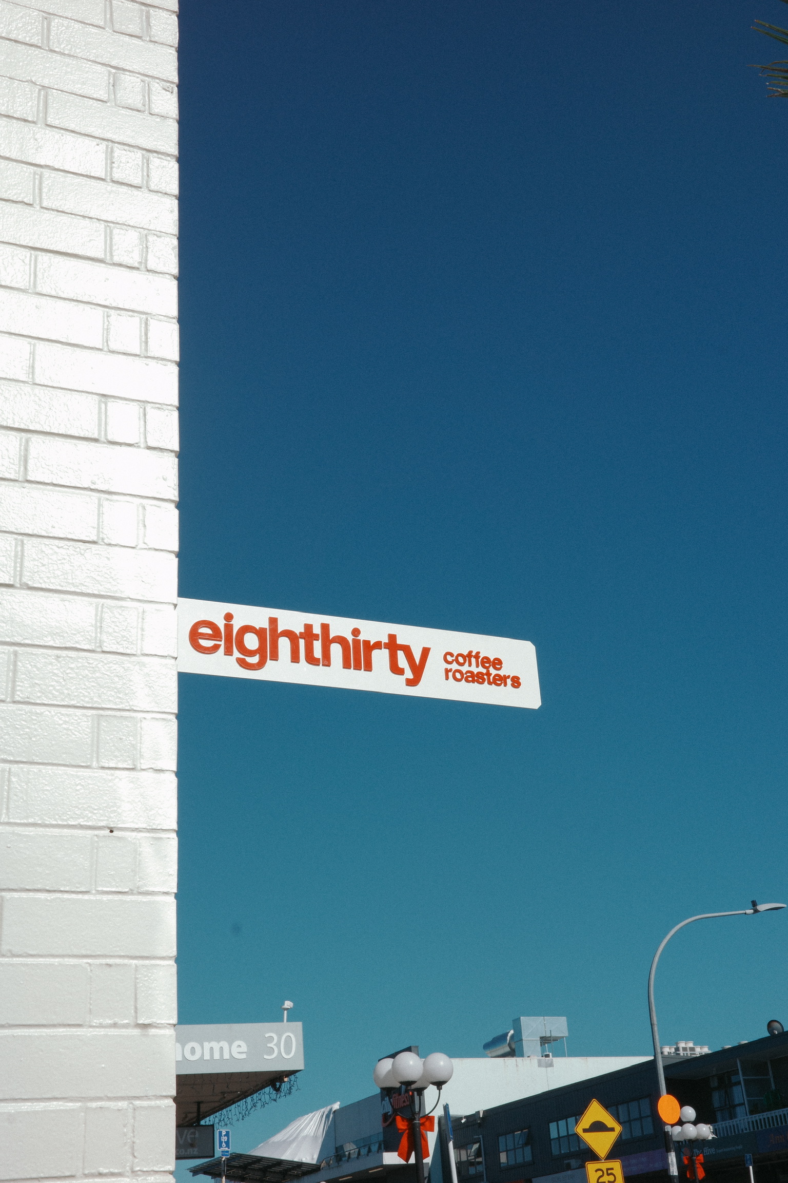 Eighthirty Coffee Roasters sign on a white-brick wall against a deep blue sky.